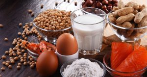 eggs, milk, salmon, prawns and nuts all displayed on a table